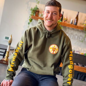 Man wearing a green hoodie with branding sitting in a casual setting.