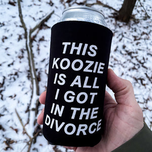 Black can cooler with white text held in a hand against a snowy background